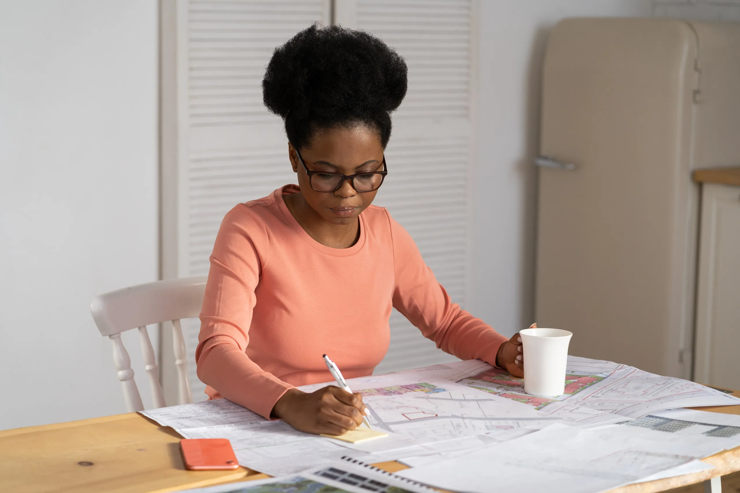 A provider working through floor plans and paperwork at her kitchen table.